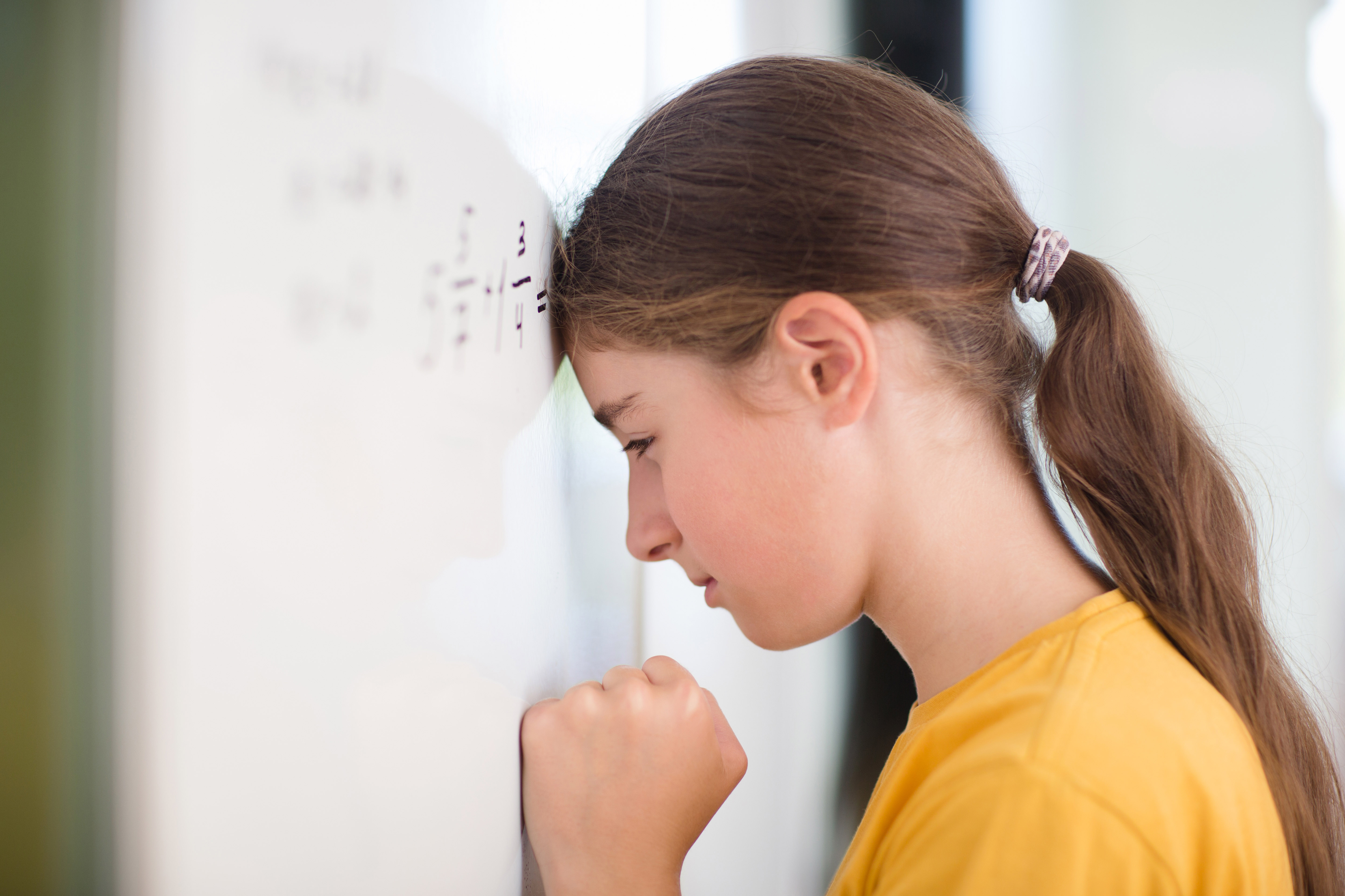 frustrated tired student is standing at blackboard and can't solve math example. problems and difficulties of studying at school.